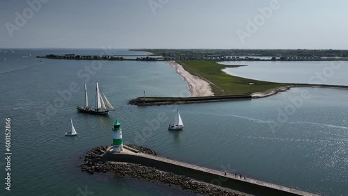 Aerial footage of a tall ship and a sailing boat passing through the entrance from the Baltic Sea into the Schlei with Olpenitz in the background. The lighthouse of Lotseninsel (pilot island).  photo