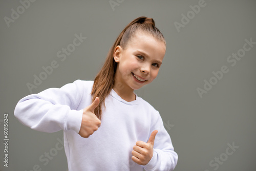 smiling girl show gesture by hands on grey scale wall background. Like gest