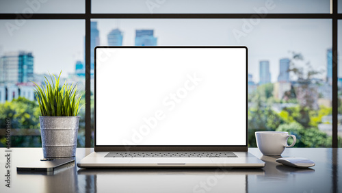 A laptop with a blank frameless screen mockup template is positioned on a table in an office interior, offering a front view, with office buildings in the background. 3d render