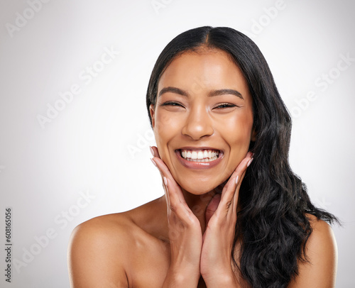 Hair, beauty and hands on face of happy woman in studio for cosmetics, treatment and shine on grey background. Smile, portrait and haircare for female model with volume, texture and keratin results