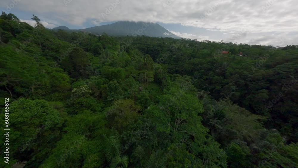 Aerial view straight cinematic flight to volcano over Asian countryside village landscape with tropical greenery vegetation. FPV sport shot drone flying natural volcanic mountain with cloud sky jungle Aerial view straight cinematic flight to volcano over Asian countryside village landscape with tropical greenery vegetation. FPV sport shot drone flying natural volcanic mountain with cloud sky jungle