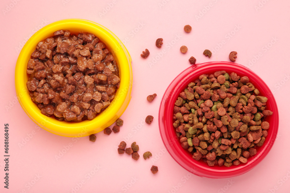 Wet and dry pet food in feeding bowls on pink background. Wet and dry pet food in feeding bowls on pink background.