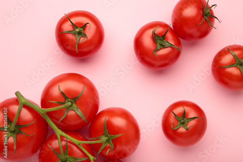 Flat lay composition with bunch of tomatoes on pink background. Space for text