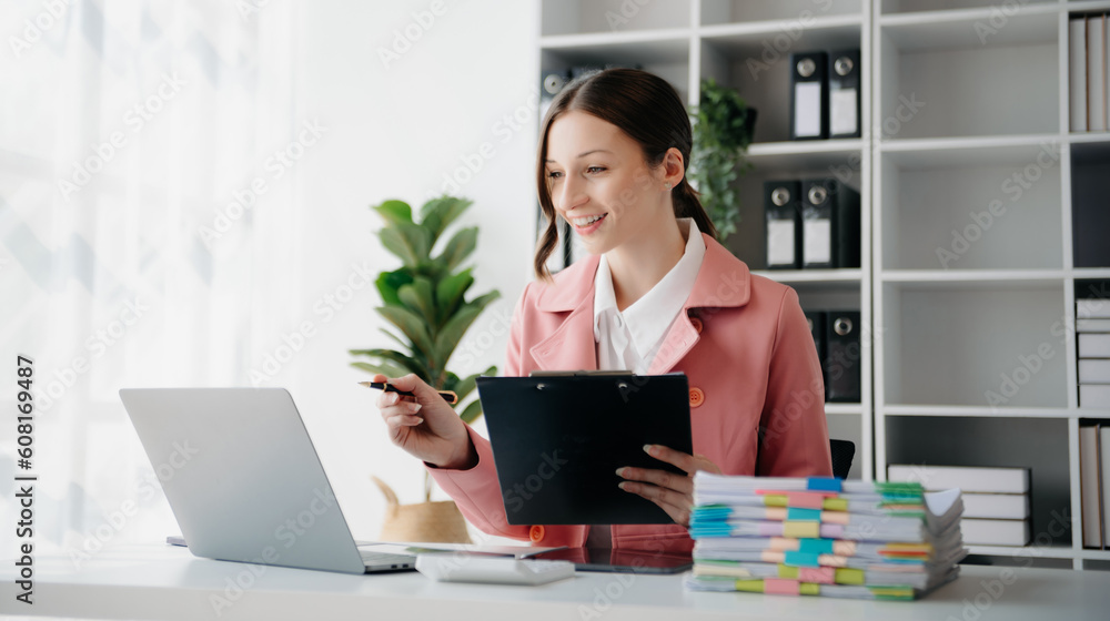 Beautiful woman using laptop and tablet while sitting at her working place. Concentrated at work. Beautiful woman using laptop and tablet while sitting at her working place. Concentrated at work.