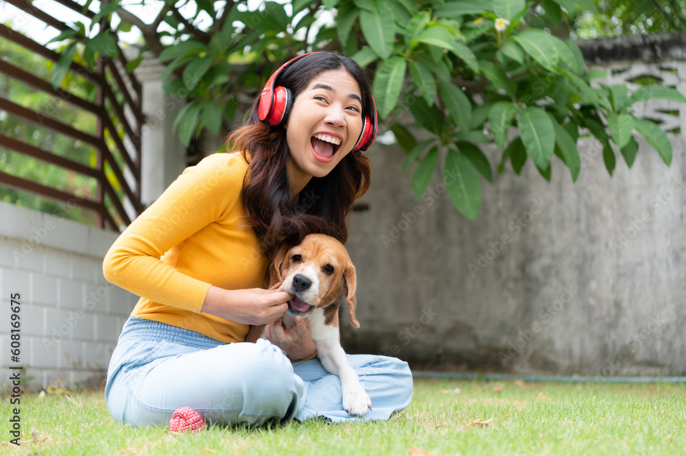 Young asian woman and beagle puppy relaxing on weekends in the front yard. Young asian woman and beagle puppy relaxing on weekends in the front yard.