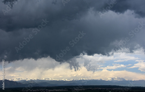 ominous afternoon storm clouds  in early summer over the snow-capped front range of the colorado rocky mountains as seen from Broomfield, colorado  © Nina
