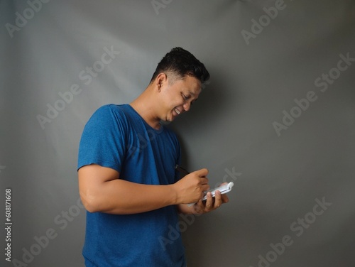 Young asian man shocked when he looking and pointing smartphone photo