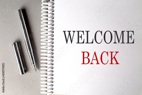 WELCOME BACK text on a notebook with pen on grey background