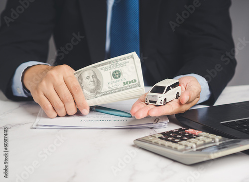 Car loan or Auto title loan. US dollar bills in a hand businessman while sitting at the table