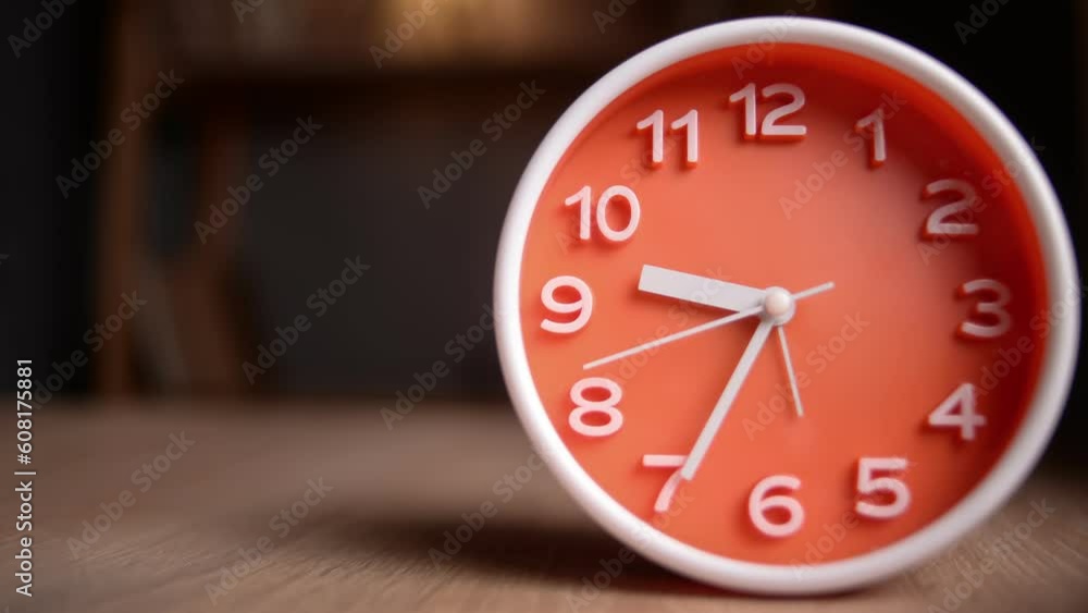 Time lapse of a orange clock on table. The clock starts ticking at 9