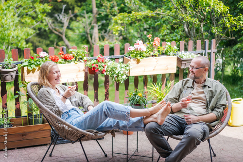 Happy middle aged caucasian couple enjoying a summer day drinking wine on the terrace of a country house. Summer lifestyle portrait