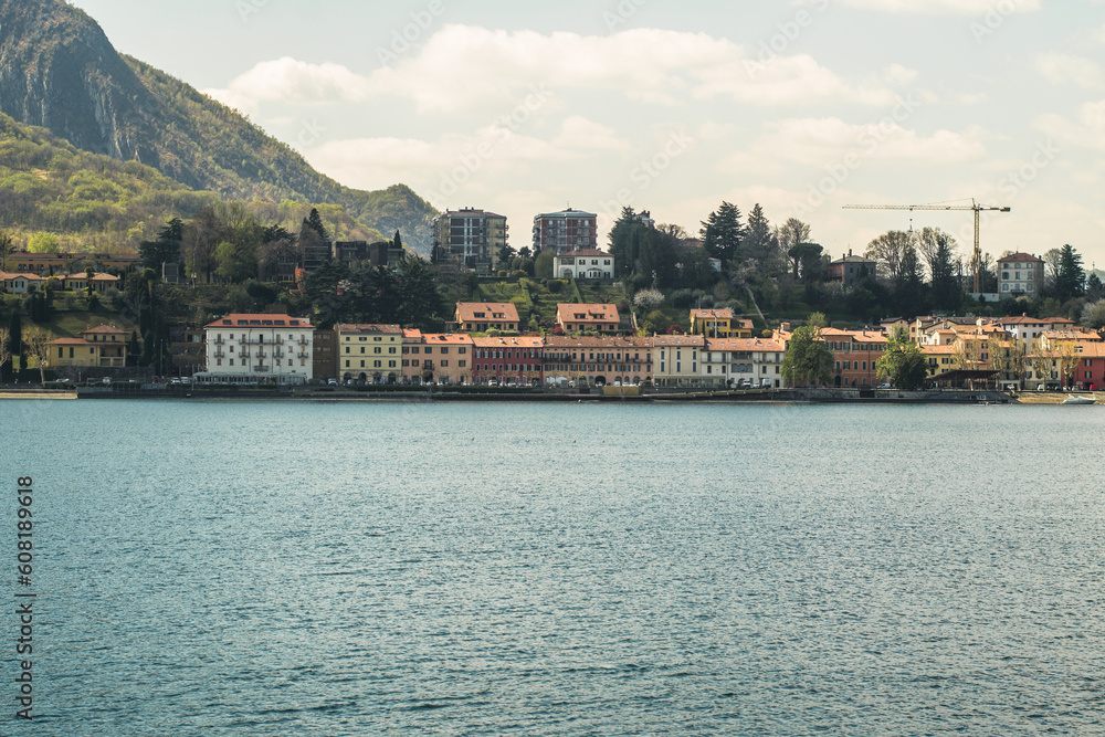 Fototapeta premium Lake Como from the shore of the city of Lecco. View of the Alps mountains, buildings and the town of Malgrate. 