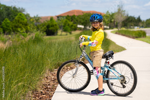 Boy in a helmet riding bike. Boy in safety helmet riding bike in city park. Child first bike. Kid outdoors summer activities. Kid on bicycle. Little child riding bike in summer park on a driveway.