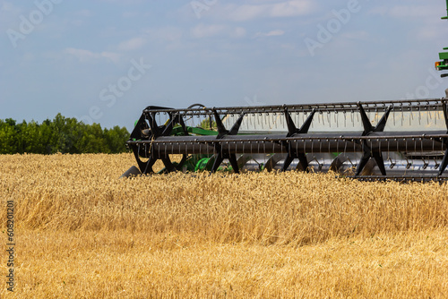 Photo of combine harvester that is harvesting wheat with dust straw in the air