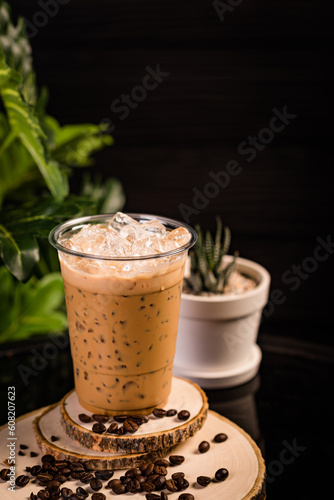 iced cappuccino coffee In a glass ready to serve Beautifully decorated with green leaves and coffee beans on a black background.