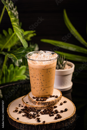 iced cappuccino coffee In a glass ready to serve Beautifully decorated with green leaves and coffee beans on a black background.