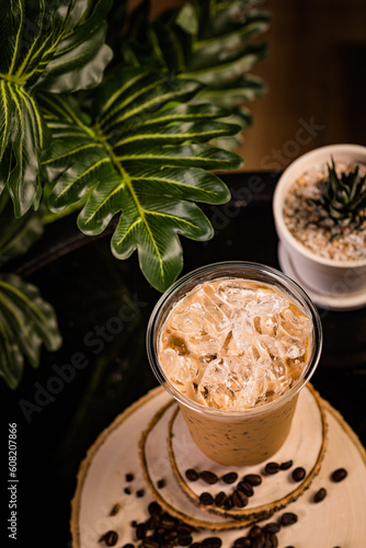 iced cappuccino coffee In a glass ready to serve Beautifully decorated with green leaves and coffee beans on a black background.