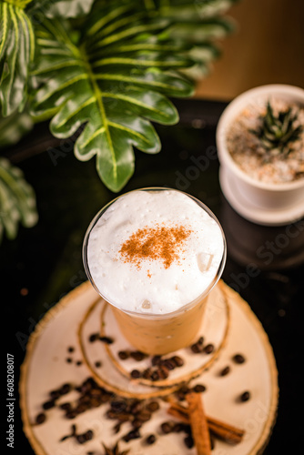 iced cappuccino coffee In a glass ready to serve Beautifully decorated with green leaves and coffee beans on a black background.