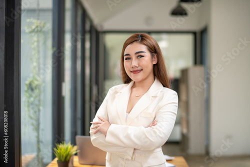 Shot of businesswoman standing front of her table in office. Smile and look at camera. vertical image