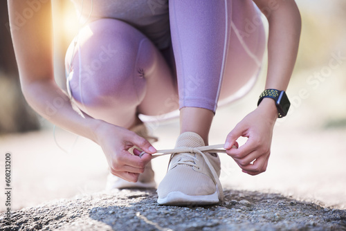 Woman  hands and tie shoes for running  exercise or workout on asphalt road or street outdoors. Hand of female person or runner tying shoe getting ready for walk  run or fitness exercising in nature