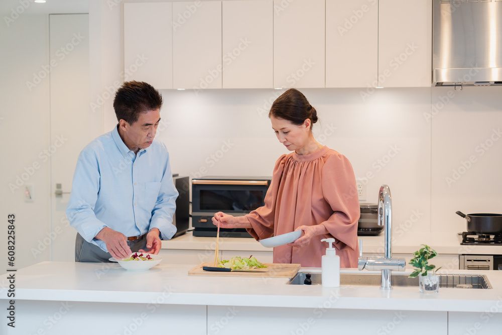 Fototapeta premium キッチンで一緒にクッキングを楽しむシニアの夫婦