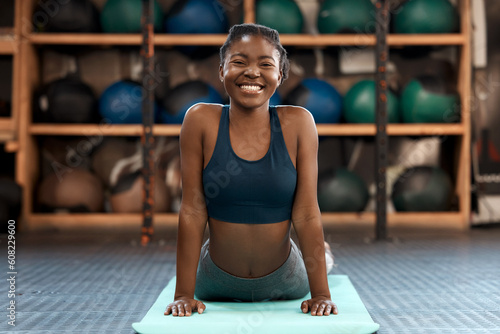 Happy black woman, portrait and yoga stretching at gym for healthy exercise, workout or cardio training. African female person or yogi with smile in warm up or svanasana pose on mat for fitness photo