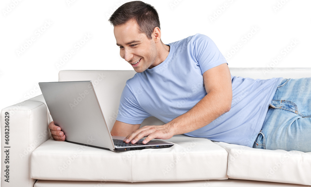 Smiling Man Using Laptop while Lying on a Couch Smiling Man Using Laptop while Lying on a Couch