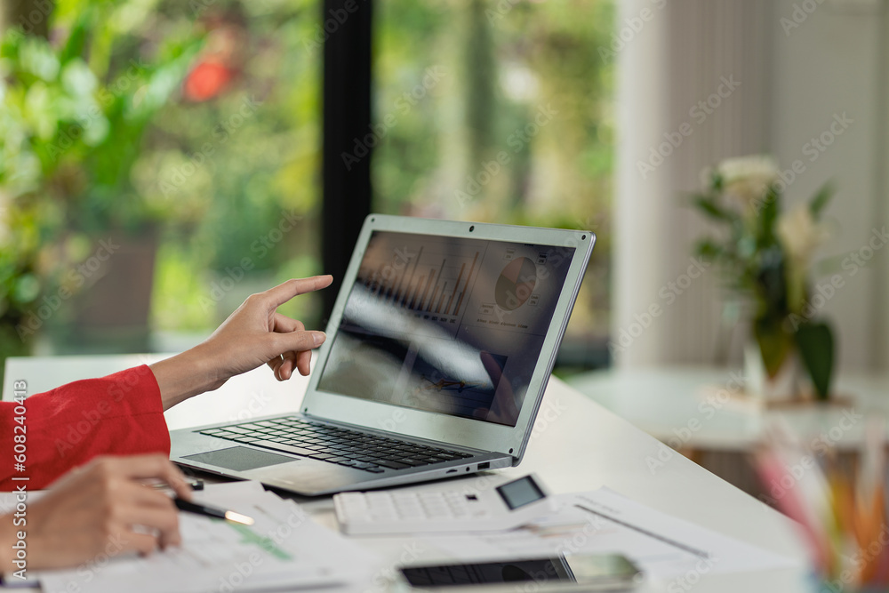 Asian businesswoman analyzes reports pointing to graphs, holding pens using laptops, business contacts, consulting to plan, financial statements, remote pictures. Asian businesswoman analyzes reports pointing to graphs, holding pens using laptops, business contacts, consulting to plan, financial statements, remote pictures.
