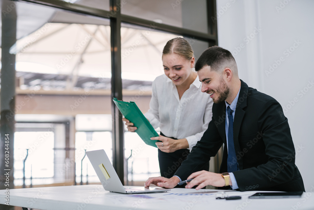 Fototapeta premium Handsome businessman and happy female employee working together in the office technology collaboration concept.
