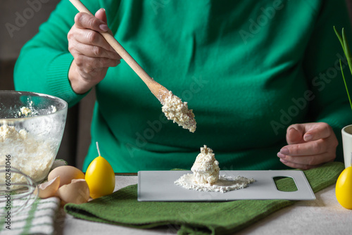 Foto Senior woman adds spoonful of dough with cottage cheese to the flour on cutting board
