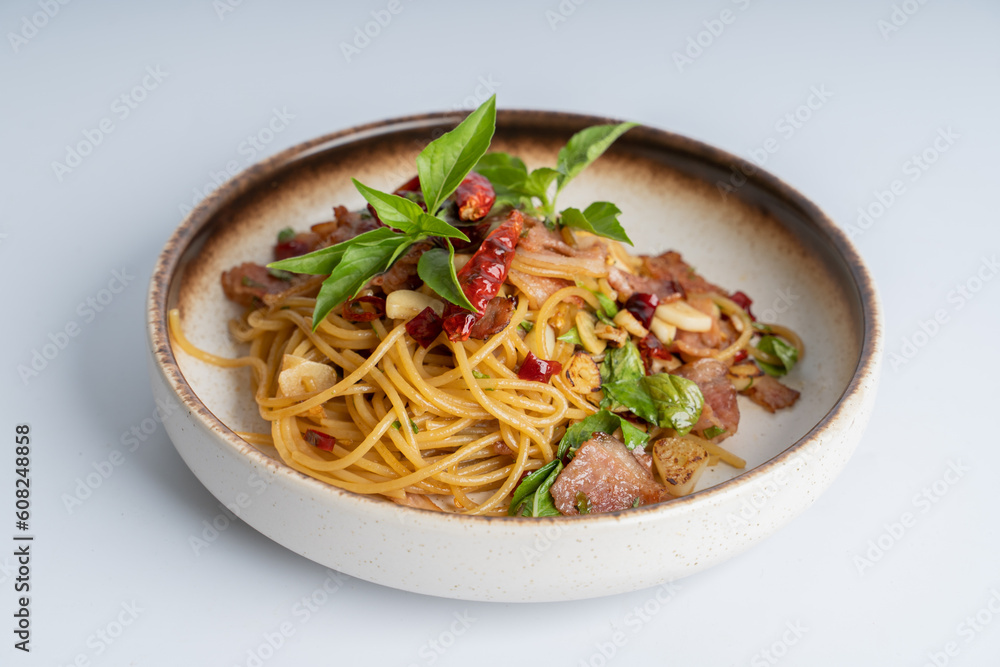 Spicy Thai basil pork pasta on white dish with white background. Italian food fusion Thai food. Tasty appetizing Italian fusion spicy spaghetti pasta with meat, chili, Thai basil. Italian fusion food. Spicy Thai basil pork pasta on white dish with white background. Italian food fusion Thai food. Tasty appetizing Italian fusion spicy spaghetti pasta with meat, chili, Thai basil. Italian fusion food.