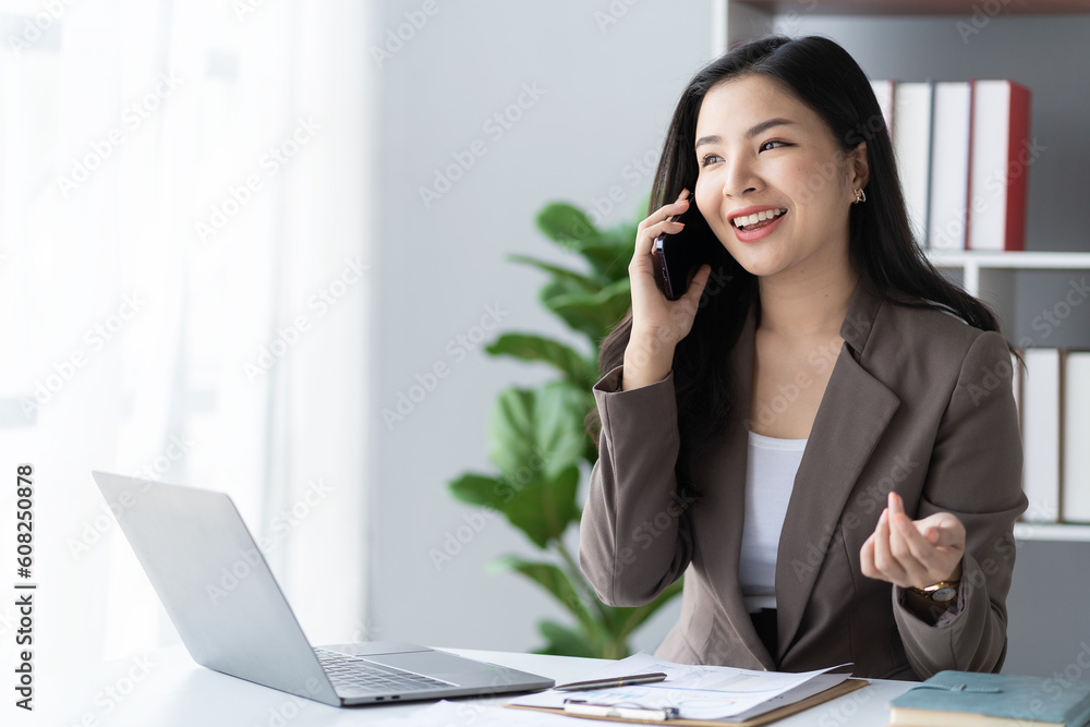 Young Asian businesswoman talking on the phone She is a salesperson at a start-up company. She calls customers to sell products and promotions. financial accounting concept Young Asian businesswoman talking on the phone She is a salesperson at a start-up company. She calls customers to sell products and promotions. financial accounting concept