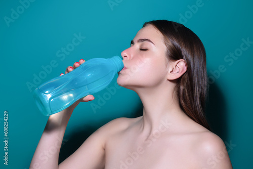 Woman drinking fresh water, isolated on studio background. Female model holds glass of clear water. Health care. Mineral water refreshment, dehydration. Portrait of woman drinking water.