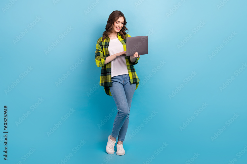 Full length photo of positive nice person use wireless netbook networking isolated on blue color background Full length photo of positive nice person use wireless netbook networking isolated on blue color background