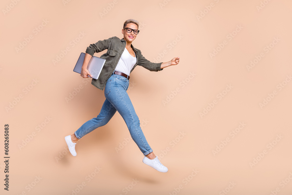 Full length photo of cheerful sweet lady dressed khaki shirt jumping high modern device emtpy space isolated color background