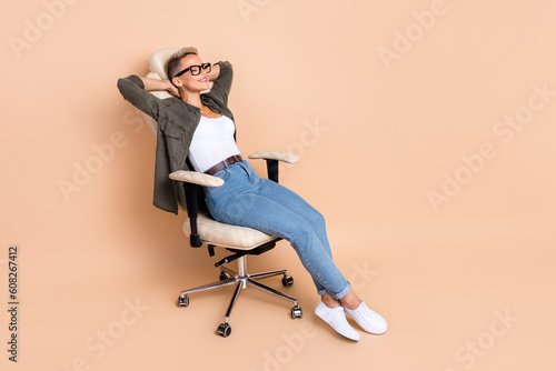 Full length photo of dreamy cute lady dressed khaki shirt arms behind head empty space isolated beige color background