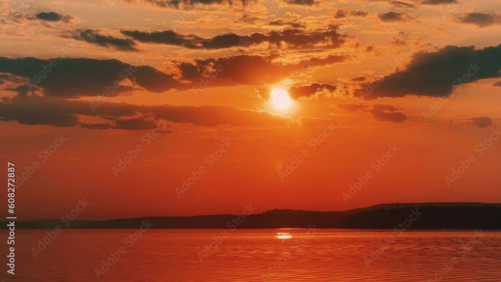A solar eclipse during a mesmerizing fiery sunset. Majestic sunset or sunrise landscape. Sunset with reflection in the water. The sun and clouds were reflected in the water. Fiery sunset. Russia