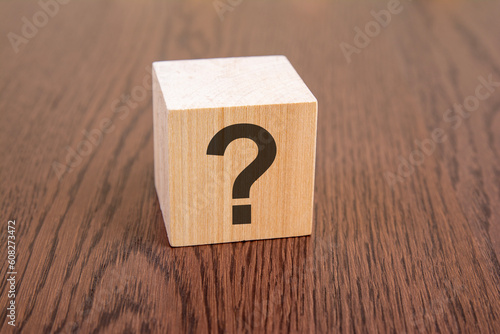 question mark drawn on a wooden cube with copy space on a dark wooden table