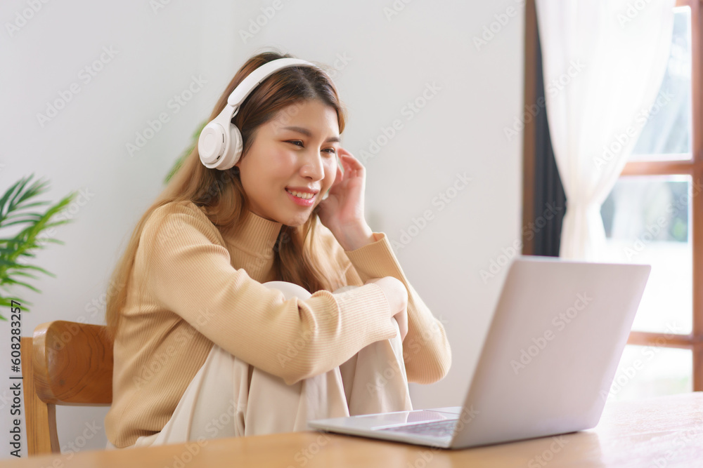 Work from home concept, Young Asian woman sitting on the chair and wear headphone to watching movie Work from home concept, Young Asian woman sitting on the chair and wear headphone to watching movie