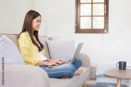 Leisure activity concept, Young woman is chatting with friends on laptop while sitting on the couch