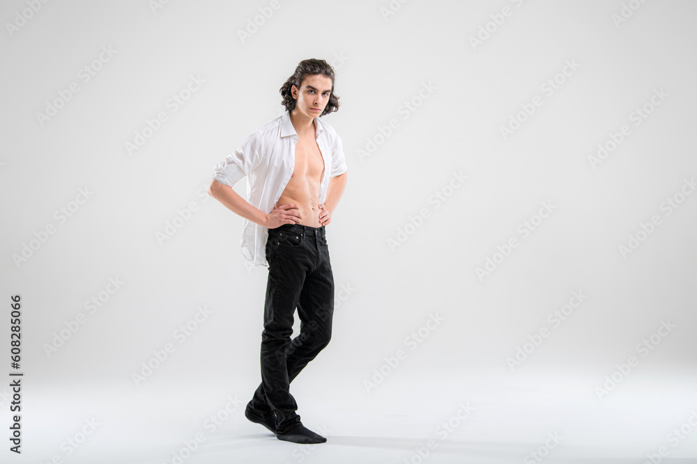 Full-length portrait of a standing handsome young man model in a white shirt and jeans on a white background. Full-length portrait of a standing handsome young man model in a white shirt and jeans on a white background.