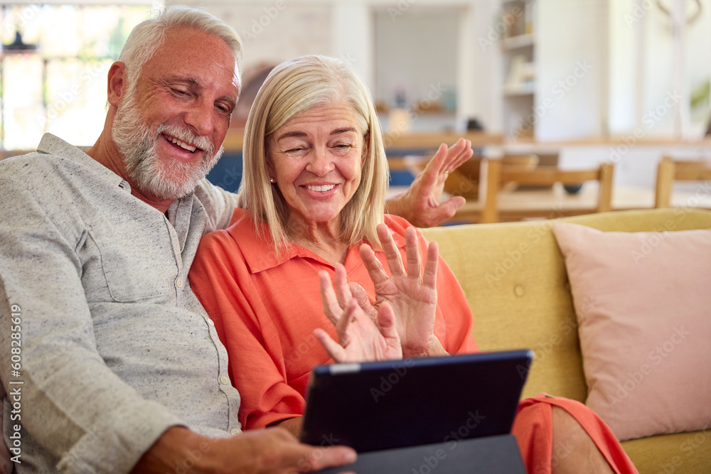 Retired Senior Couple At Home Making Video Call On Digital Tablet Retired Senior Couple At Home Making Video Call On Digital Tablet