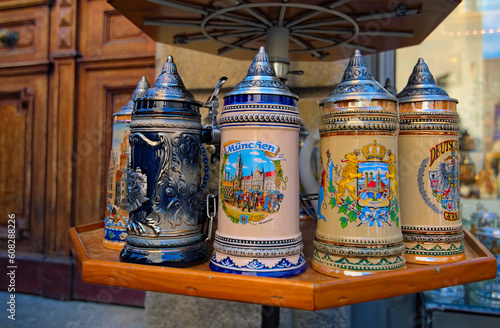 Munich Germany-April 30,2018:Close-up view of beautiful decorated ceramic beer cups in souvenir shop. Colorful beer mugs in wooden shelf. Beer mugs are depicting the architecture of Munich