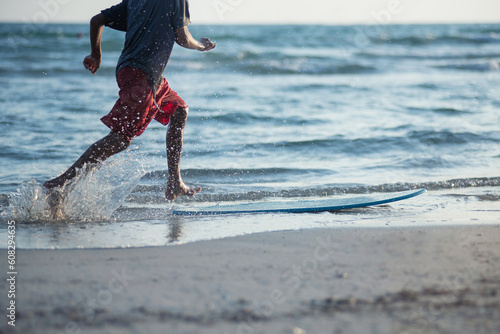 Photography Boy practice to ride skim board on the beach, boy with surfboard on sunset beach