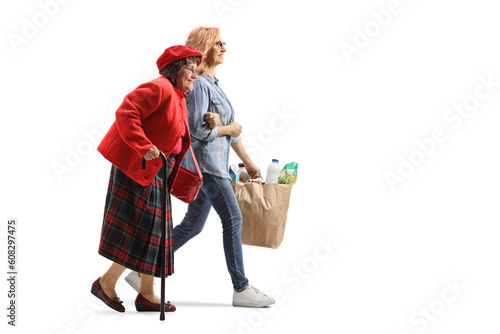 Full length profile shot of a woman helping an elderly woman and carrying grocery bags photo