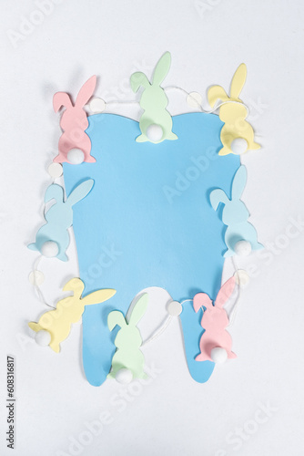 Easter dentistry. Blue tooth and garland of rabbits on a white background, top view © Zarina Lukash