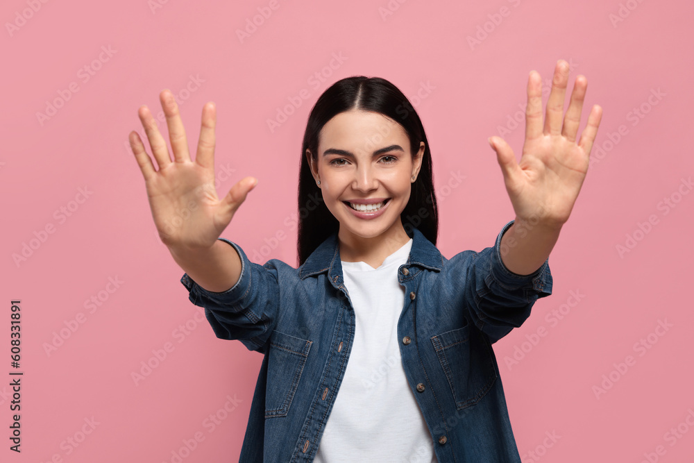 Happy woman giving high five with both hands on pink background Happy woman giving high five with both hands on pink background