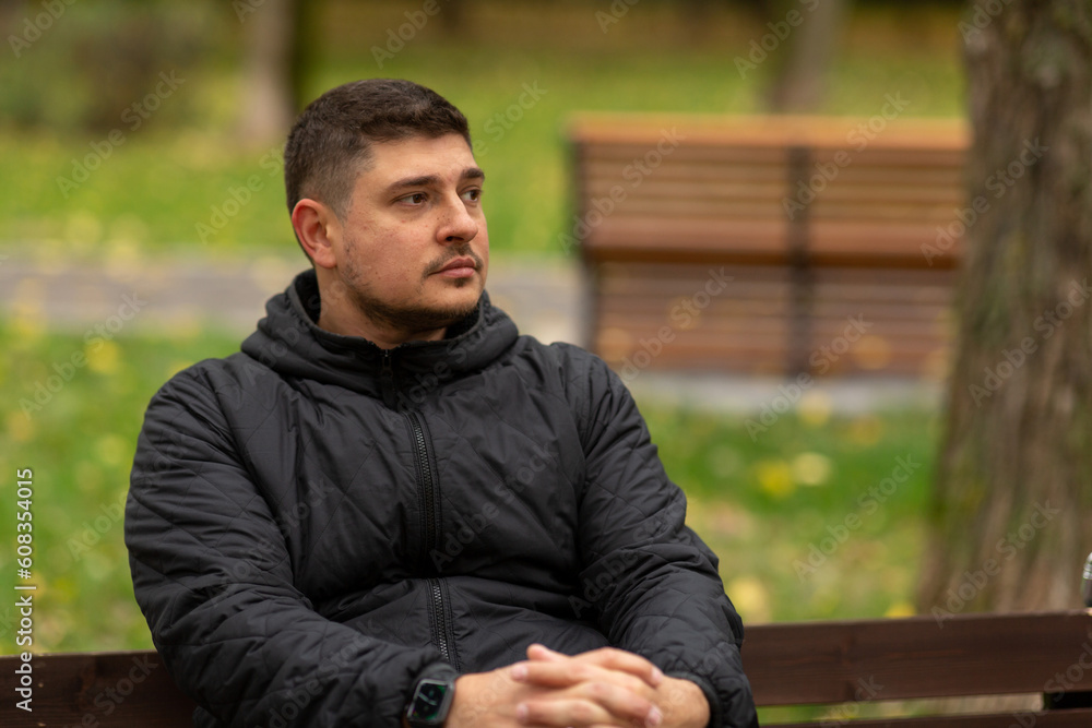 A man is sitting on a bench in the park in autumn A man is sitting on a bench in the park in autumn