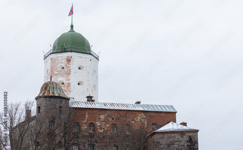 White tower of Vyborg Castle is under bright cloudy sky