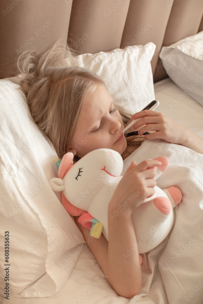 The girl measures the temperature in bed. The child got sick. The girl measures the temperature in bed. The child got sick.